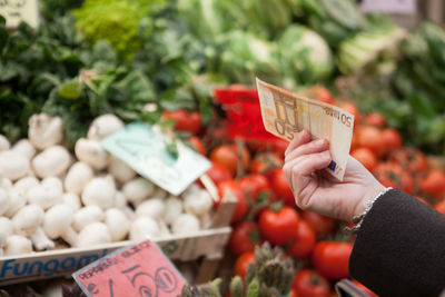 Hand holding vegetables for sale at market stall