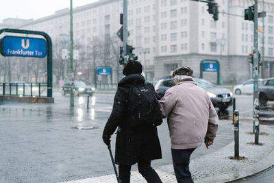 Rear view of people walking on road in city