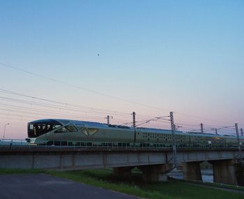 Train by railroad tracks against clear sky