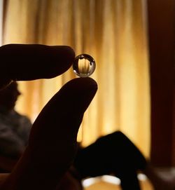 Close-up of hand holding crystal ball at home