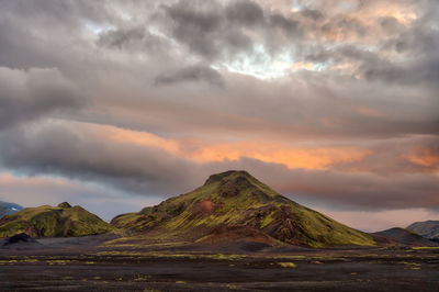 Scenic view of sea and mountains against dramatic sky