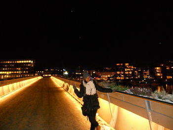 Rear view of man walking on illuminated street at night