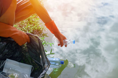 Midsection of woman holding bottle in water