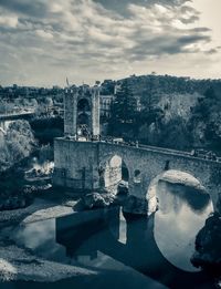 Arch bridge over river against buildings