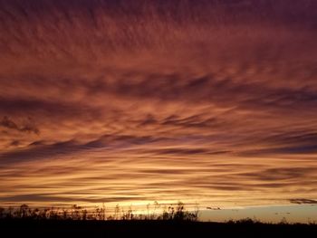 Silhouette landscape against dramatic sky during sunset