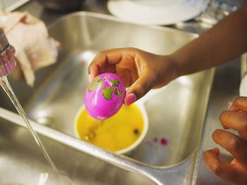 Cropped hands of woman holding easter egg in kitchen