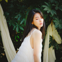 Beautiful young woman standing by plants