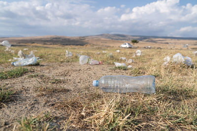 Scattered plastic bottles and bags lie on grass in rural area causing pollution of environment