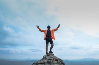 Full length of man standing on rock against sky