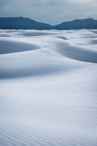 Scenic view of sand covered landscape against blue sky in white sands national park