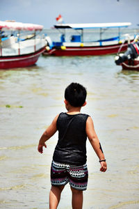 Rear view of boy standing on shore at beach