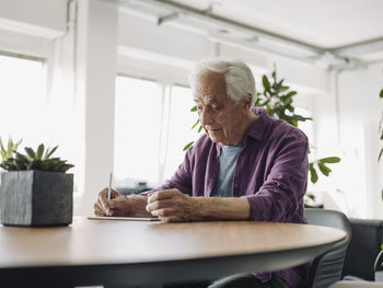 Businessman using digital tablet while sitting by table at office