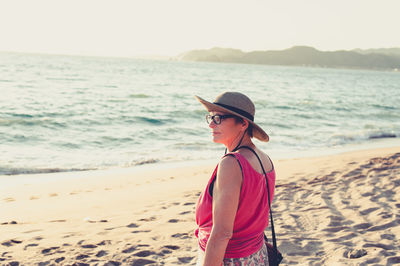 Senior woman smiling and looking at the ocean at the beach