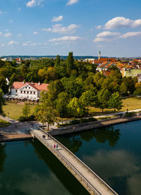 Swimming pool by lake and buildings against sky