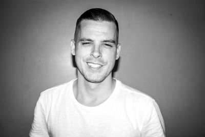 Portrait of smiling young man by wall
