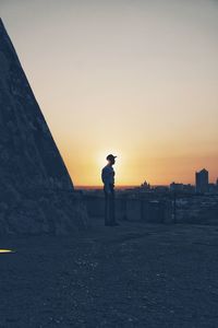 Side view of man standing against sky during sunset