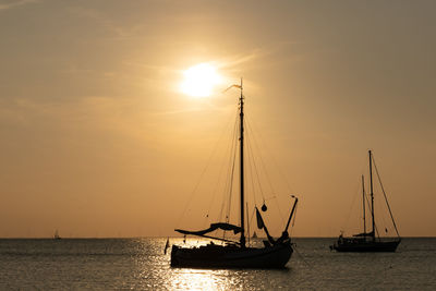 Sailboats sailing in sea against sky during sunset