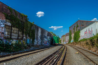 Railroad tracks amidst buildings against blue sky