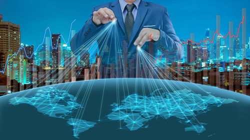 Digital composite image of businessman managing global business in illuminated city at night