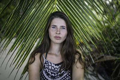 Portrait of beautiful young woman against tree