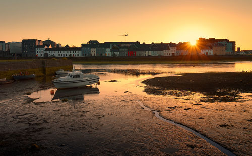 Beautiful sunrise scenery of colorful houses and boat reflected in corrib river at claddagh, galway
