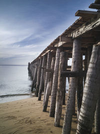 Wooden posts on beach against sky