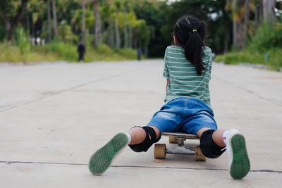 Rear view of woman skateboarding on footpath