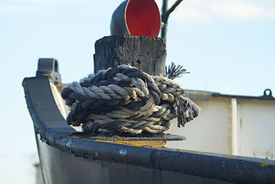 Close-up of rope tied on wooden post against sky