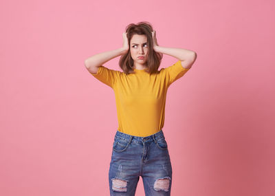 Portrait of woman standing against pink background