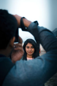 Close-up of man photographing woman against sky