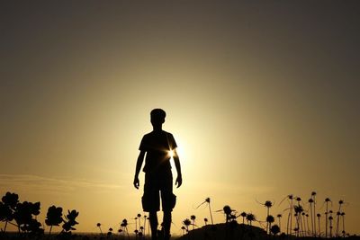 Silhouette of woman standing on landscape at sunset