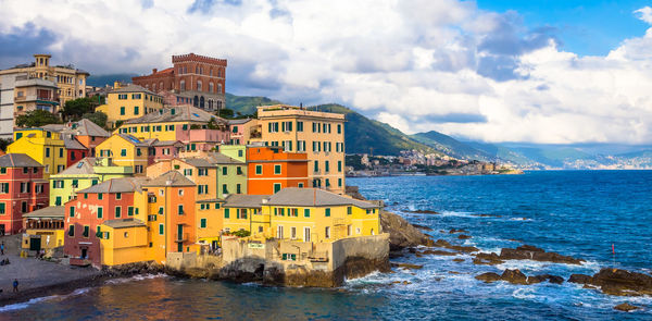 Buildings by sea against sky