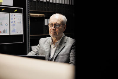 Portrait of businessman using laptop while standing in office