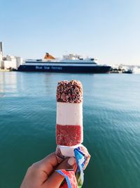 Midsection of person holding ice cream in water