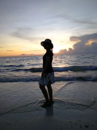 Full length of woman standing on beach during sunset