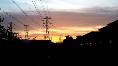 Low angle view of electricity pylon against cloudy sky