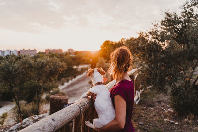 Side view of woman sitting in park against sky