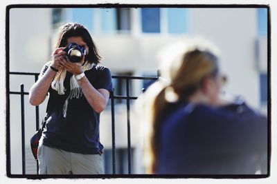 Portrait of young woman photographing through smart phone