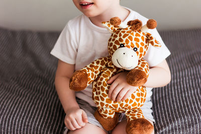 Child  holding a giraffe plush toy on a gray background