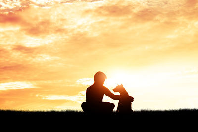 Silhouette man sitting on field against sky during sunset
