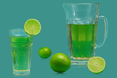 Green fruits with drink against glass background