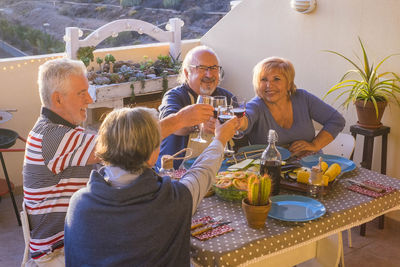 Senior couples toasting drinks while sitting at dining table