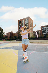 Woman dancing with ribbon and roller skating at sports court