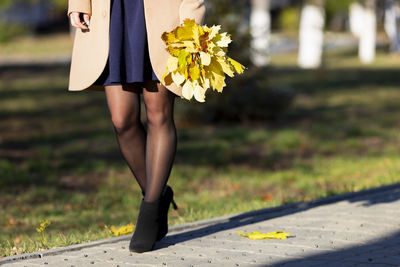 Low section of woman standing on yellow flower