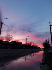 Silhouette trees and electricity pylon against sky during sunset