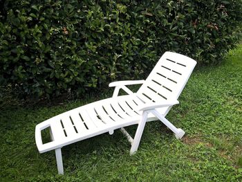 Empty lounge chair on field against plant