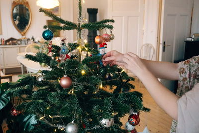 Cropped hands decorating christmas tree