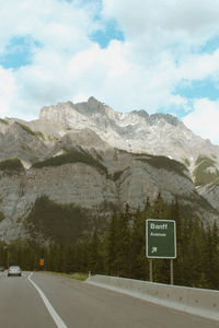 Road sign by mountains against sky