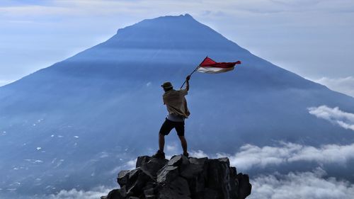 Full length of man standing on rock against sky