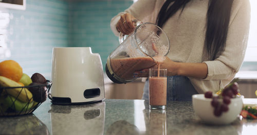 Midsection of woman holding drink at table